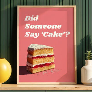Framed poster with a cake illustration and text on a pink background, placed on a wooden shelf against a green wall.