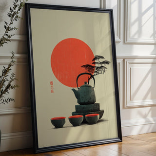 Framed artwork of a teapot and cups with a red sun on a beige background, placed on a wooden floor.