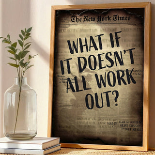 Framed New York Times article on a wicker table with a vase and books.