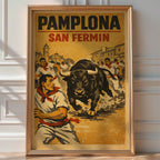 Vintage 'Pamplona San Fermín' poster of runners fleeing a charging bull through the streets